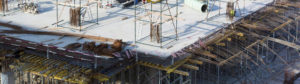 Construction site showing a multi-level building. There is a concrete floor with visible rebar and scaffolding is set up on top of the floor. 